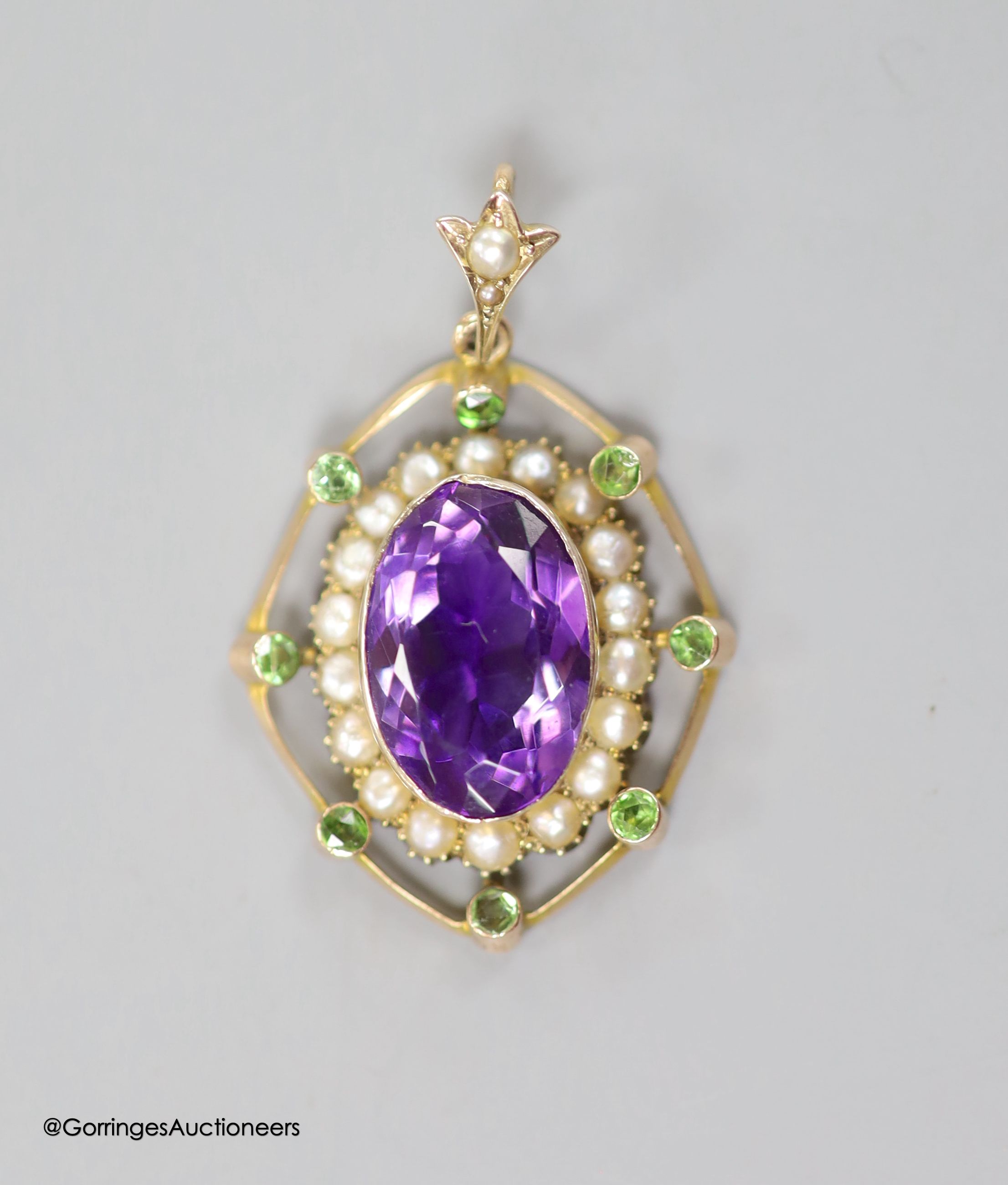 An early 20th century yellow metal, amethyst, split pearl and green stone set oval pendant, in the Suffragette colours, overall 39mm, gross weight 5.5 grams (a.f.).
